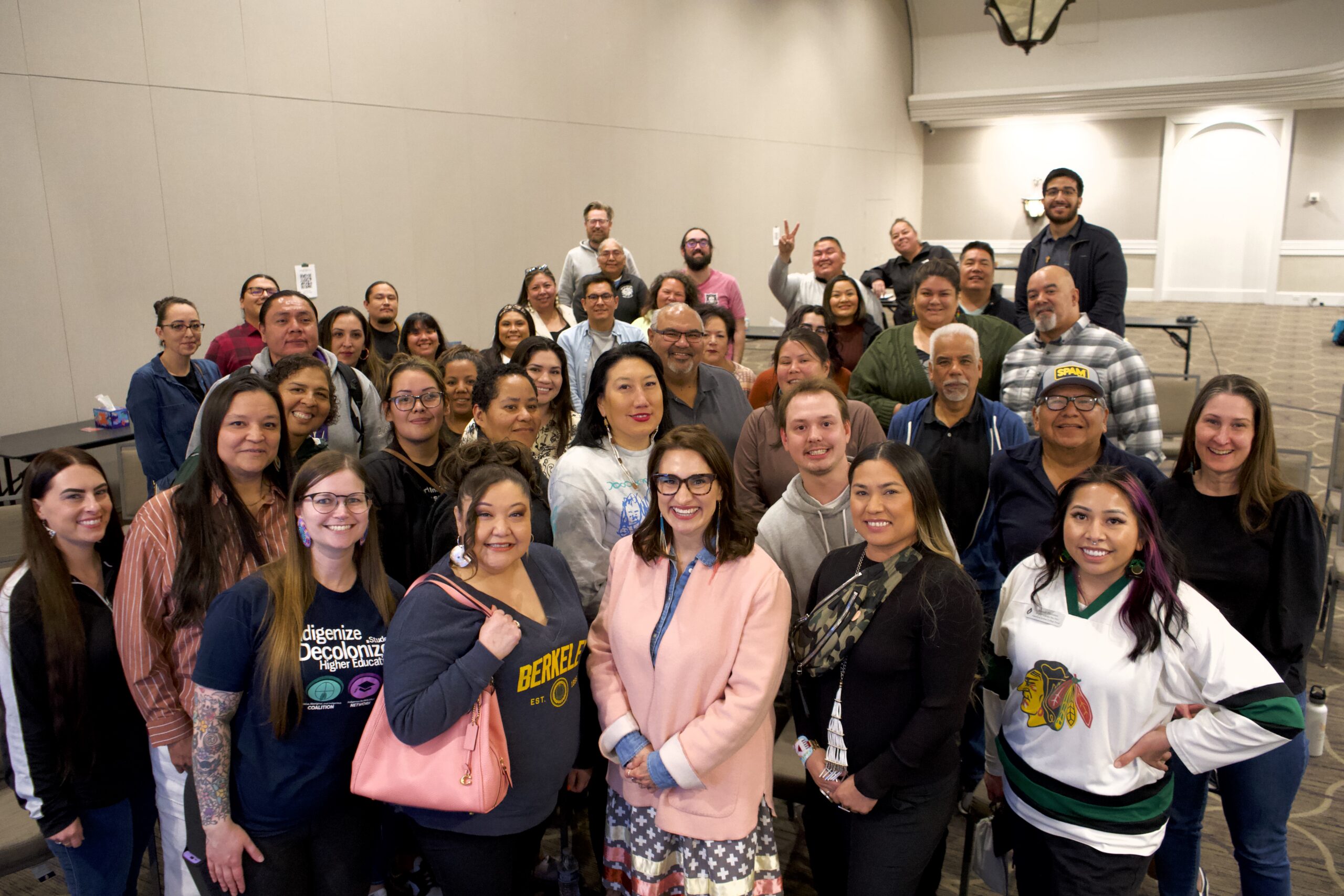 A large group of Cobell Scholars and community members gathered together indoors, smiling for a group photo.
